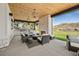 Inviting outdoor living area featuring a fireplace, built-in grill, wooden ceiling, and comfortable seating at 15191 Dinosaur Ridge Rd, Morrison, CO 80465