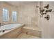 Bathroom featuring a tub, tile walls, a tiled seat, and dual glass block windows at 5530 E 6Th Ave Pkwy, Denver, CO 80220