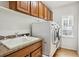 Well-equipped laundry room with sink, wooden cabinets, and a side window at 6296 S Rifle St, Aurora, CO 80016