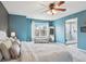 Bright main bedroom featuring a ceiling fan, large window, ensuite bathroom, and neutral carpet at 6296 S Rifle St, Aurora, CO 80016