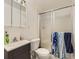 Compact bathroom with a white toilet, sliding glass shower, and vanity with a dark gray cabinet at 9832 Kenton Cir, Commerce City, CO 80022