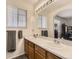 Bathroom with double sinks, a large mirror with vanity lighting, and wood cabinets at 9832 Kenton Cir, Commerce City, CO 80022