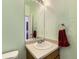 Well-lit half bathroom featuring a vanity with a white sink, wood cabinet, and mint green walls at 9832 Kenton Cir, Commerce City, CO 80022