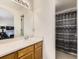 Main bathroom featuring a vanity, framed mirror, wood cabinets, and tiled shower at 9832 Kenton Cir, Commerce City, CO 80022