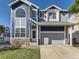 Charming two-story home boasts blue siding, stone accents, a manicured lawn, and an attached two-car garage at 9832 Kenton Cir, Commerce City, CO 80022