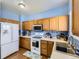Functional kitchen with wooden cabinets, white appliances, and laminate floors and a blue wall at 9832 Kenton Cir, Commerce City, CO 80022