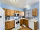 Functional kitchen with wooden cabinets, white appliances, and laminate floors and a blue wall at 9832 Kenton Cir, Commerce City, CO 80022
