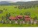Stunning aerial view of a sprawling property with lush green fields and a charming home with a red roof at 5939 Lone Peak Dr, Evergreen, CO 80439