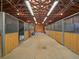 Barn interior with multiple stalls, wooden beams, and ample lighting at 5939 Lone Peak Dr, Evergreen, CO 80439