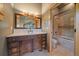 Bathroom with a wood cabinet, marble countertop, framed mirror, and a glass-enclosed shower and bathtub at 5939 Lone Peak Dr, Evergreen, CO 80439