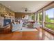 Cozy living room with stone fireplace, hardwood floors, and large windows offering scenic views at 5939 Lone Peak Dr, Evergreen, CO 80439