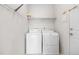 Bright laundry room features a white washer and dryer, shelving, and hanging rack for convenience at 4069 S Abilene Cir # E, Aurora, CO 80014