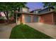 Charming two-story home features a brick facade, two-car garage, and well-manicured lawn, complemented by mature trees and an American flag at 12545 Elm St, Thornton, CO 80241