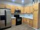 Bright kitchen with stainless steel appliances, wood cabinets, and modern lighting at 14400 Albrook Dr # 88, Denver, CO 80239