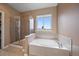 Bathroom featuring a soaking tub next to a glass enclosed shower and a large window at 22873 E David Pl, Aurora, CO 80016
