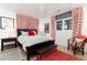 The bedroom features a wood floor, a wooden bed frame, and red decor at 3925 S Cherry St, Englewood, CO 80113