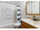 Clean bathroom with a tub/shower combo, gray striped curtain and a wood-trimmed vanity at 9698 Pecos St, Thornton, CO 80260