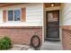 Close-up of an entryway with a brick facade, a storm door, and shuttered windows at 9698 Pecos St, Thornton, CO 80260
