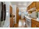Efficient kitchen with wood cabinetry, white appliances, and a view into the dining area at 9698 Pecos St, Thornton, CO 80260