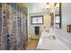 Bright bathroom with double sinks, a framed mirror, and a shower featuring a patterned curtain at 1300 Kennedy Dr, Northglenn, CO 80234