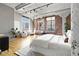 Bright bedroom features exposed brick, concrete ceilings, and large windows with city views at 1863 Wazee St # 6E, Denver, CO 80202
