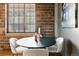 Dining area with a brick wall, black table, white chairs, hardwood floors, and lots of natural light at 1863 Wazee St # 6E, Denver, CO 80202