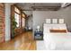Spacious main bedroom showcasing exposed brick, hardwood floors, a modern rug, and ample natural light at 1863 Wazee St # 6E, Denver, CO 80202