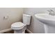 Half-bath with modern white pedestal sink and toilet with wood-look flooring at 3823 Horiuchi St, Brighton, CO 80601