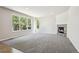 Living room with plush gray carpet, stone fireplace, and bright natural lighting at 3823 Horiuchi St, Brighton, CO 80601