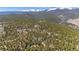 Scenic aerial view of the mountain property surrounded by lush trees and snow-capped peaks in the background at 14800 Gold Hill Rd, Boulder, CO 80302