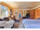 Comfortable bedroom featuring wood-paneled walls, seating area, walk-in closet, and ample natural light at 14800 Gold Hill Rd, Boulder, CO 80302