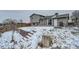 This fenced backyard with terraced landscaping, patio, and back deck in the snow at 2723 E 96Th Way, Thornton, CO 80229