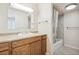 Well-lit bathroom features a light wood vanity, a full mirror, and a shower-tub with a patterned shower curtain at 10211 Ura Ln # 3-104, Thornton, CO 80260