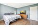 Bedroom with a bed, a TV on a bureau, and blue walls with wooden trim at 10211 Ura Ln # 3-104, Thornton, CO 80260
