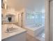 Bright bathroom featuring an extended vanity counter and large soaking tub with glass block window at 7672 E Arizona Dr, Denver, CO 80231