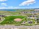 A panoramic view of a community park features a baseball field, playground, and beautiful lake backdrop at 9510 Orion Way, Arvada, CO 80007
