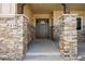 Close up of a covered front porch with stone columns, wood trim, and a stylish front door at 9510 Orion Way, Arvada, CO 80007