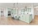 Bright kitchen features a large center island with pendant lighting, light green cabinets, and stainless steel appliances at 9510 Orion Way, Arvada, CO 80007