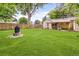 A spacious backyard with a well-maintained lawn, wooden fence, and a charming stone fire pit for outdoor enjoyment at 2680 S Garfield Cir, Denver, CO 80210