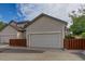 Side view of home featuring a two-car garage, a brown fence, and low-maintenance landscaping at 18324 E Bethany Pl, Aurora, CO 80013