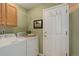 Functional laundry room features a washer, dryer, overhead cabinet, and stylish door hooks at 18324 E Bethany Pl, Aurora, CO 80013