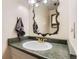 Bathroom featuring a decorative mirror, gold-colored faucet, and a green countertop at 8613 Santa Fe Dr, Thornton, CO 80260
