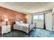 Bedroom showcasing a brick accent wall, iron bed frame, and soft blue carpet at 8613 Santa Fe Dr, Thornton, CO 80260