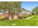 Charming townhouse with red brick and lush green lawn with walkway and mature trees in a well-maintained community at 8613 Santa Fe Dr, Thornton, CO 80260