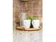 Close-up of kitchen decor items including two white mugs, a glass jar, and a plant sitting on a wooden tray at 5920 Garrison St, Arvada, CO 80004