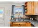 Corner kitchen featuring a stainless steel sink, granite countertops, and a sunlit window with blue curtains at 5920 Garrison St, Arvada, CO 80004