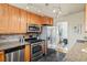 Practical kitchen featuring stainless steel appliances, wooden cabinetry, and a view into an adjacent dining area at 5920 Garrison St, Arvada, CO 80004