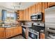 Functional kitchen with stainless steel appliances, granite countertops, wooden cabinets, and a double basin sink under the window at 5920 Garrison St, Arvada, CO 80004