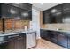 Modern kitchen with dark cabinets, granite countertops, stainless steel dishwasher, and stylish brick backsplash at 2566 N Emerson St, Denver, CO 80205