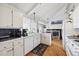 Bright eat-in kitchen with white cabinetry, white appliances, and hardwood floors at 12391 E Cedar Cir, Aurora, CO 80012